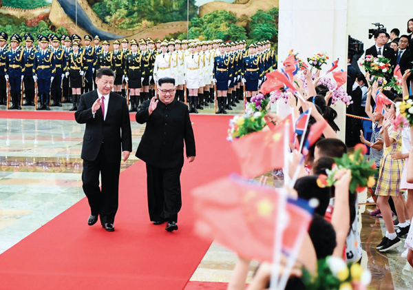 6월 19일 중국을 방문한 김정은 위원장이 베이징 인민대회당에서 열린 환영식에서 시진핑 국가주석과 함께 걸으며 손을 흔들고 있다.