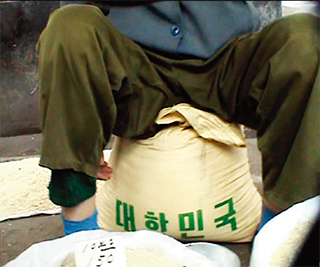 2003년 한국이 제공한 쌀이 ‘당당히’ 유통되던 북한의 장마당. 북한 금융은 말라가고 있기에 북한 인민들은 자력으로 물품을 마련해야 하는 상황에 몰리고 있다.